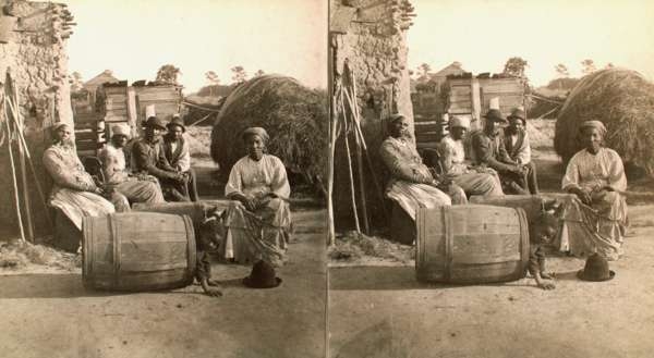 Adults Seated, Facing Camera, Child Playing in Barrel in Foreground, Plantation Setting